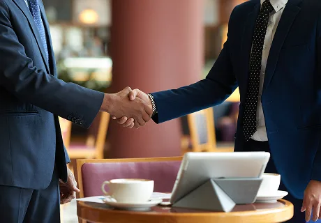 Two people shaking hands over a business meeting